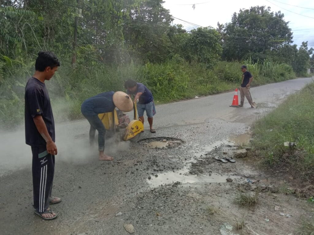 PERBAIKAN JALAN: Pekerja saat melakukan perbaikan jalan berlubang dengan metode aspal dingin.