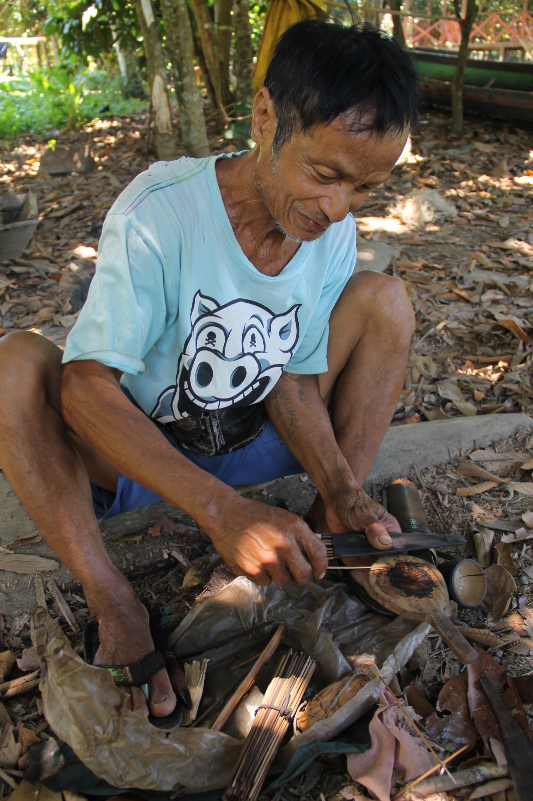 SUMPIT BERACUN: Kakek Luling saat meracik racun sumpit dari getah Kayu Tajom yang dipanaskan hingga mengental kemudian dioleskan keujung anak sumpit. (Foto: Dedi Suhendra)